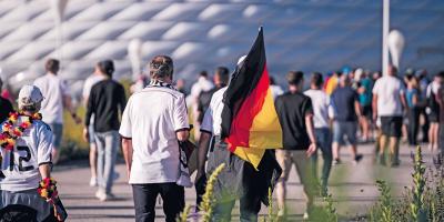 Fußballfans auf dem Weg zur Arena mit deutscher Fahne
